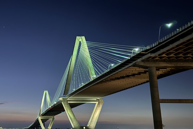 Ravenel Bridge cables and tower lit up at dusk over Charleston Harbor