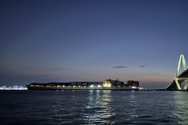 Container ship passing through Charleston Harbor at twilight with bridge in background
